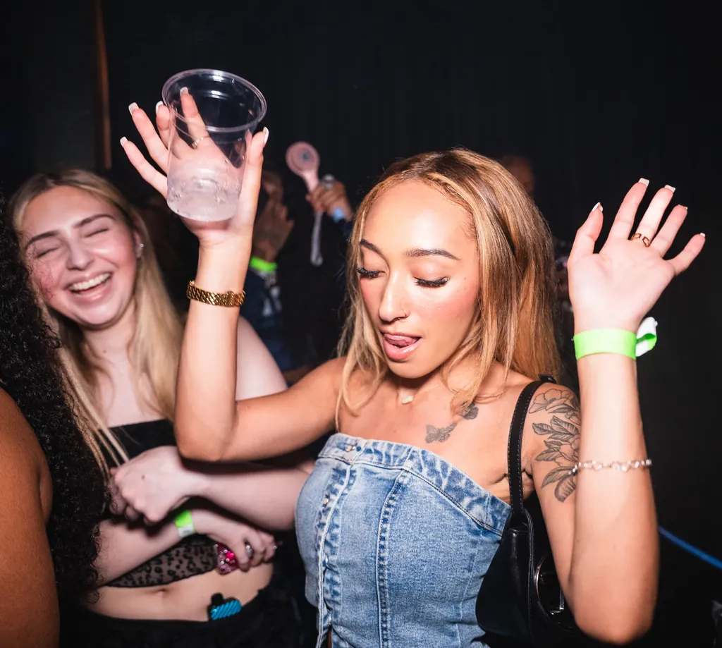 Two friends laughing and dancing with their cups in the air