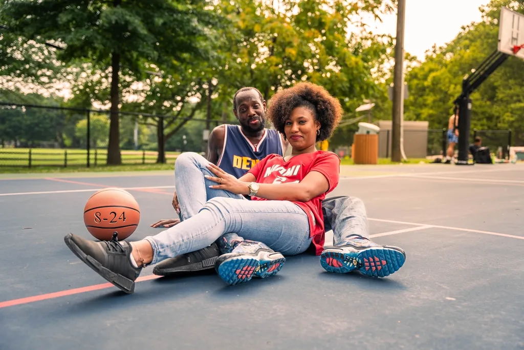 The couple sitting together on the court at golden hour, a ball marked 8-24 beside them